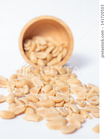 Peanuts in a wooden cup rest on a white background, creating a warm and rustic food-themed scene. Peanuts in a wooden cup rest on a white background, creating a warm and rustic food-themed scene. 141720503
