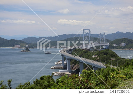 可以看到鳴門海峽大橋、藍色的大海、一艘船、一座有燈塔的無人小島、四國海岸、一座城鎮、山脈和天空。 可以看到鳴門海峽大橋、藍色的大海、一艘船、一座有燈塔的無人小島、四國海岸、一座城鎮、山脈和天空。 141720601