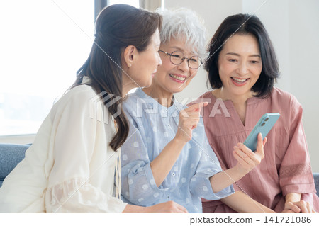 A middle-aged female friend looking at her smartphone in the living room. A middle-aged female friend looking at her smartphone in the living room. 141721086