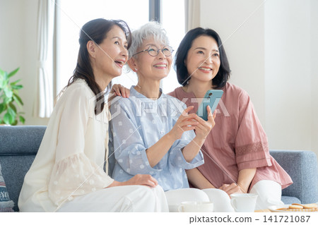 A middle-aged female friend looking at her smartphone in the living room. A middle-aged female friend looking at her smartphone in the living room. 141721087
