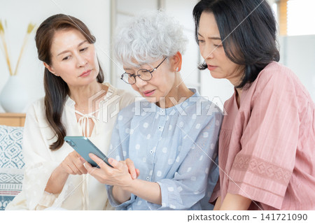 A middle-aged female friend looking at her smartphone in the living room. 141721090