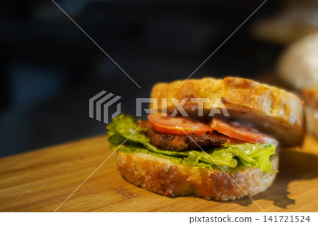 Rustic Gourmet Sandwich with Artisan Bread Tomato Lettuce and Grilled Patty on Wooden Board Rustic Gourmet Sandwich with Artisan Bread Tomato Lettuce and Grilled Patty on Wooden Board 141721524