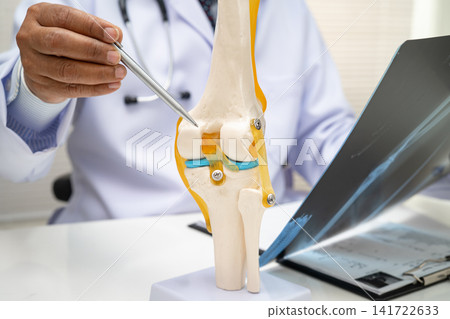 Doctor examining knee joint bone radiography xray film. Doctor examining knee joint bone radiography xray film. 141722633