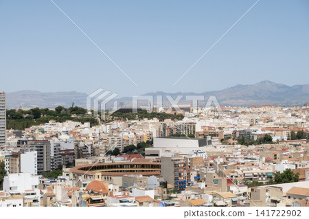 A cityscape view of Alicante, Spain, showcasing dense architecture and mountains in the background A cityscape view of Alicante, Spain, showcasing dense architecture and mountains in the background 141722902