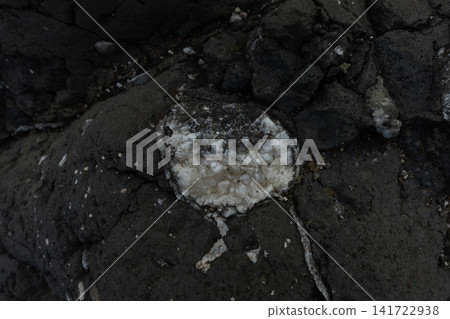 Dark volcanic rock texture with a white calcite crystal formation creating a natural pattern 141722938