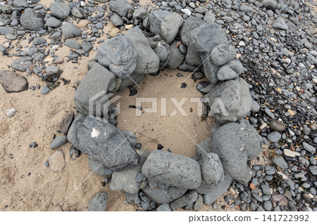 Top view of a stone campfire ring built from large rocks on a sandy beach Top view of a stone campfire ring built from large rocks on a sandy beach 141722992