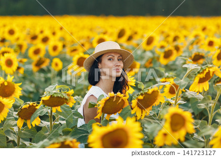 Beautiful young woman in hat on sunflower field Beautiful young woman in hat on sunflower field 141723127