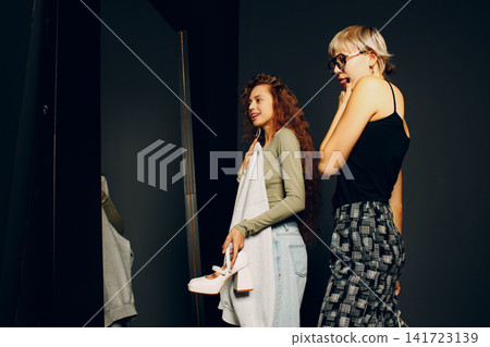 Beautiful young woman stylist designer helping choose clothes to customer client Beautiful young woman stylist designer helping choose clothes to customer client 141723139