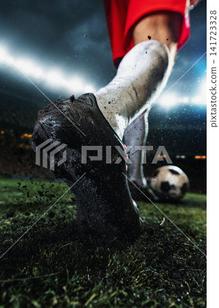 Mud-caked football sole and studs filling foreground with soccer ball blurred behind Mud-caked football sole and studs filling foreground with soccer ball blurred behind 141723328