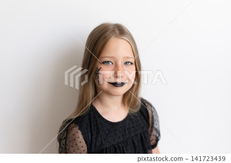 Girl in witch costume smiling gently on white background Girl in witch costume smiling gently on white background 141723439