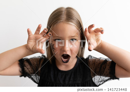Close up portrait of little girl growling with claw hands for Halloween Close up portrait of little girl growling with claw hands for Halloween 141723448