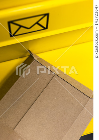 Brown parcel rests near a yellow mailbox at a self service kiosk, highlights modern convenience and streamlined mailing. Brown parcel rests near a yellow mailbox at a self service kiosk, highlights modern convenience and streamlined mailing. 141723647