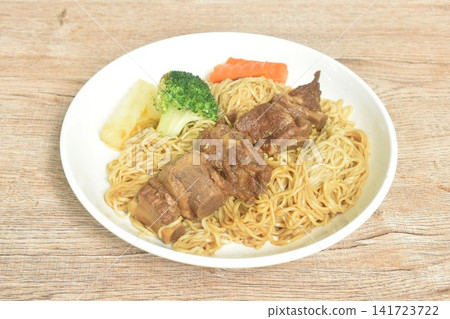 Chinese yellow egg nodles topping braised slice honey pork bone stew dressing black herb sauce with boiled vegetable on plate Chinese yellow egg nodles topping braised slice honey pork bone stew dressing black herb sauce with boiled vegetable on plate 141723722
