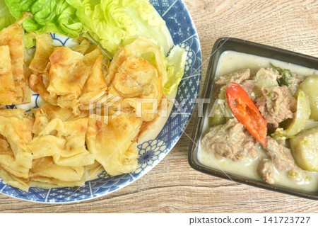 crispy roti eat couple spicy boiled slice beef meat with lemon leaf and eggplant in coconut milk green curry soup on bowl crispy roti eat couple spicy boiled slice beef meat with lemon leaf and eggplant in coconut milk green curry soup on bowl 141723727