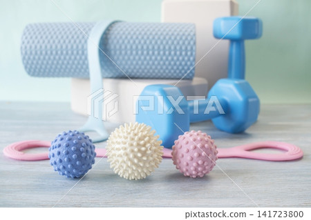 Fitness equipment and massage balls for training and recovery. Fitness equipment for yoga and pilates with dumbbells and massage balls on studio background. Fitness equipment and massage balls for training and recovery. Fitness equipment for yoga and pilates with dumbbells and massage balls on studio background. 141723800