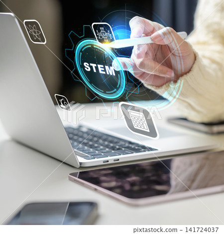 Close-up of a female using a stylus to interact with a digital STEM interface hovering above a laptop, representing science, technology, engineering, and mathematics education. STEM education concept 141724037