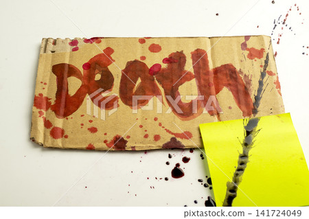 A close-up of a cardboard sign with the word Death written in red blood stains and splatters, placed next to a bright yellow sticky note on a white background. Concept of Halloween A close-up of a cardboard sign with the word Death written in red blood stains and splatters, placed next to a bright yellow sticky note on a white background. Concept of Halloween 141724049
