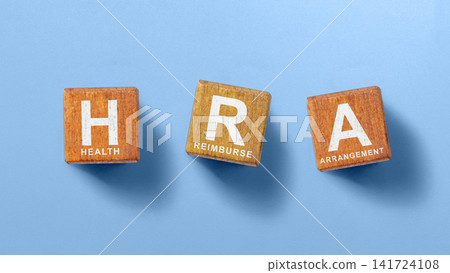 Wooden letter blocks spelling HRA (Health Reimbursement Arrangement) on a blue background. Concept of Reimburse 141724108