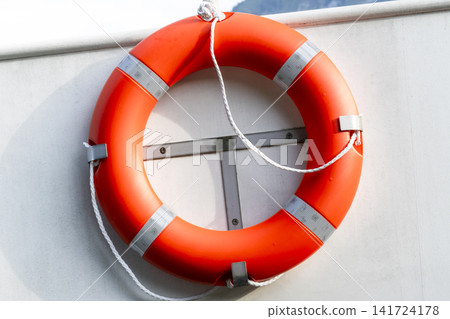 Bright orange lifebuoy on board a boat, illustrating maritime safety and the clean aesthetic of marine objects Bright orange lifebuoy on board a boat, illustrating maritime safety and the clean aesthetic of marine objects 141724178