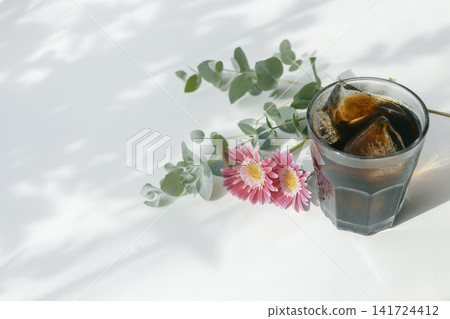 一張令人神清氣爽的夏日咖啡館圖片,畫面中有冰咖啡、非洲菊和尤加利葉。 一張令人神清氣爽的夏日咖啡館圖片,畫面中有冰咖啡、非洲菊和尤加利葉。 141724412
