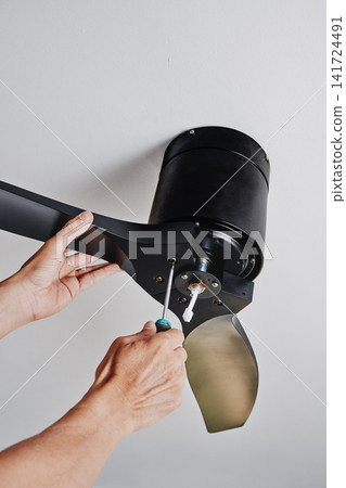 man securing a ceiling fan while installing it 141724491
