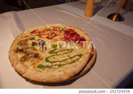 Freshly made pizza with various toppings on a white tablecloth in a cozy restaurant setting during evening hours Freshly made pizza with various toppings on a white tablecloth in a cozy restaurant setting during evening hours 141724559