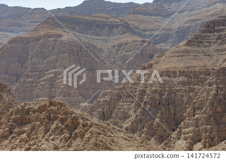 Parched desert landscape under bright sunlight showcasing striking rock formations and layered terrain Parched desert landscape under bright sunlight showcasing striking rock formations and layered terrain 141724572