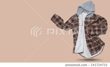 Unbuttoned brown check hooded flannel shirt levitating with copy space on beige background. Open warm fleece lined plaid shacket floating in air Unbuttoned brown check hooded flannel shirt levitating with copy space on beige background. Open warm fleece lined plaid shacket floating in air 141724733