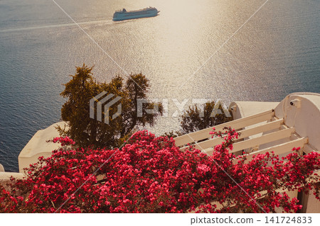 Beautiful view of pink bougainvillea flowers on traditional white terrace overlooking calm ocean with cruise ship in Santorini island Greece for travel stock photo Beautiful view of pink bougainvillea flowers on traditional white terrace overlooking calm ocean with cruise ship in Santorini island Greece for travel stock photo 141724833