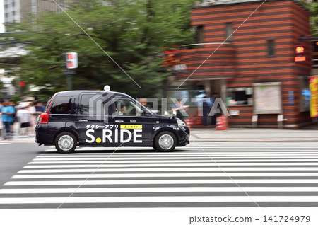 A taxi driving in front of the police box at Sukiyabashi intersection. A taxi driving in front of the police box at Sukiyabashi intersection. 141724979