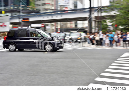 A taxi driving through Sukiyabashi intersection A taxi driving through Sukiyabashi intersection 141724980