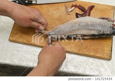 Top view of herring cleaning procedure in domestic kitchen. Top view of herring cleaning procedure in domestic kitchen. 141725434
