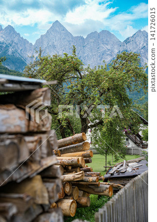 Stacked firewood and village houses in Kranjska Gora, Slovenia, with the rocky Julian Alps in the background, showing everyday alpine life and strong sense of place Stacked firewood and village houses in Kranjska Gora, Slovenia, with the rocky Julian Alps in the background, showing everyday alpine life and strong sense of place 141726015