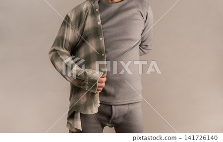 Man wearing thermal wear with open shirt in studio setting. Man wearing thermal wear with open shirt in studio setting. 141726140