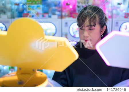 Asian Woman Concentrating on Arcade Machine Game Asian Woman Concentrating on Arcade Machine Game 141726946