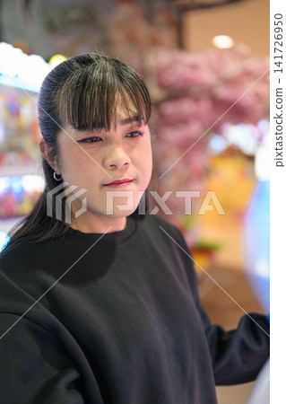Close-Up Profile of Asian Woman in Game Center Close-Up Profile of Asian Woman in Game Center 141726950