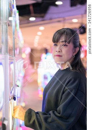 Profile View of Woman Turning Gashapon Machine Knob Profile View of Woman Turning Gashapon Machine Knob 141726956