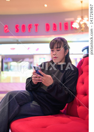 Vertical Shot of Woman Sitting and Using Mobile Phone Vertical Shot of Woman Sitting and Using Mobile Phone 141726967