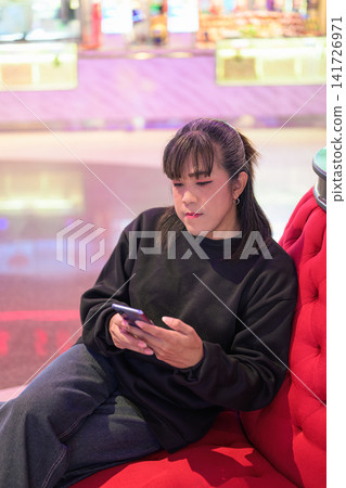 Vertical High-Angle View of Woman Using Smartphone on Sofa Vertical High-Angle View of Woman Using Smartphone on Sofa 141726971