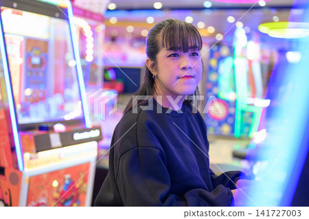 Asian Transgender Woman Smiling Near Neon Arcade Cabinets Asian Transgender Woman Smiling Near Neon Arcade Cabinets 141727003