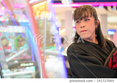 Asian Transgender Woman Looking at Claw Machine Arcade Game 141727005