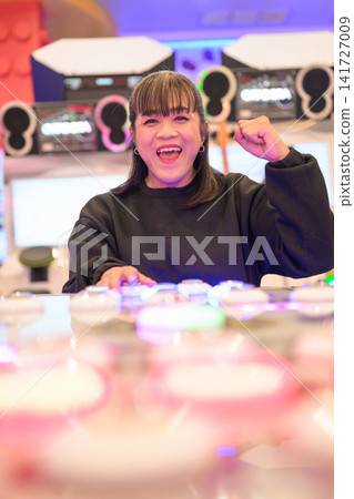 Excited Asian Woman Celebrating Game Victory in Neon Arcade Excited Asian Woman Celebrating Game Victory in Neon Arcade 141727009