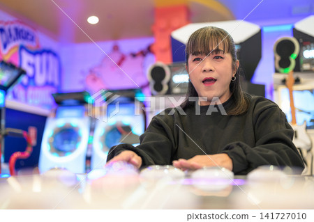 Expressive Woman Thrilled Playing Rhythm Button Game at Arcade Expressive Woman Thrilled Playing Rhythm Button Game at Arcade 141727010