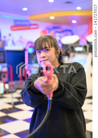 Front Perspective of Woman Aiming Pink Arcade Gun at Lens Front Perspective of Woman Aiming Pink Arcade Gun at Lens 141727017