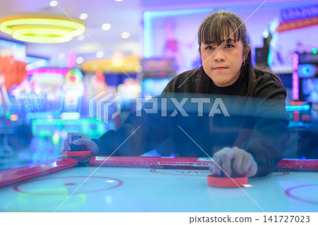 Front View of Woman Playing Air Hockey Game in Arcade Front View of Woman Playing Air Hockey Game in Arcade 141727023