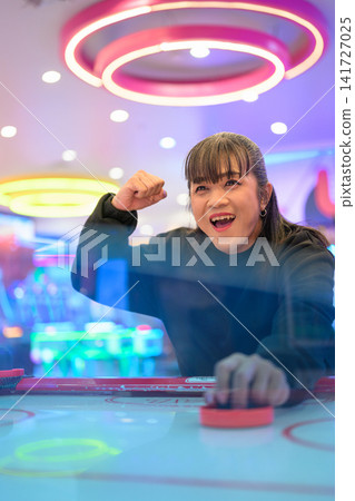 Excited Woman Celebrating Victory at Air Hockey Table Excited Woman Celebrating Victory at Air Hockey Table 141727025