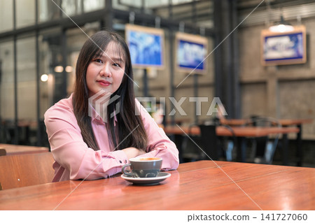 Portrait of a Confident Asian Woman Sitting in a Cafe with a Cup of Coffee Portrait of a Confident Asian Woman Sitting in a Cafe with a Cup of Coffee 141727060
