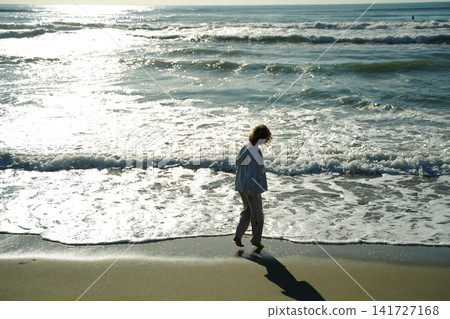 Child Walking Along the Beach with Gentle Waves Child Walking Along the Beach with Gentle Waves 141727168