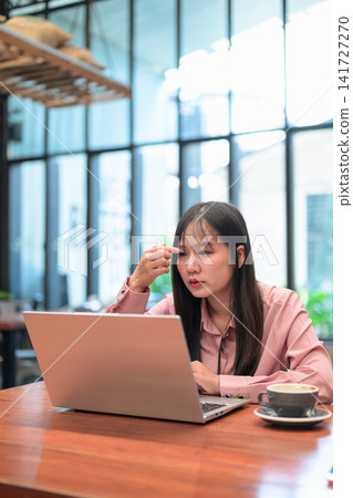 Thoughtful Asian Woman Touching Head while Looking at Laptop Thoughtful Asian Woman Touching Head while Looking at Laptop 141727270