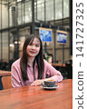 Portrait of a Confident Asian Woman Sitting in a Cafe with a Cup of Coffee 141727325